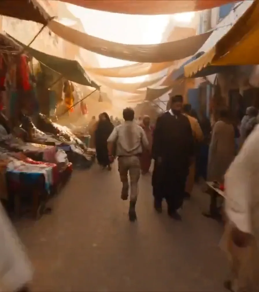 Source clip ending frame of a runner in a market alley